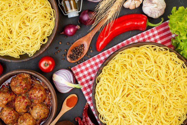 Top view tasty meatball soup in bowl spaghetti in bowl wooden spoons onions on table