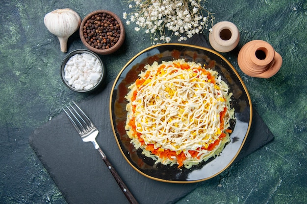 Top view of tasty mimosa salad inside plate on dark-blue surface