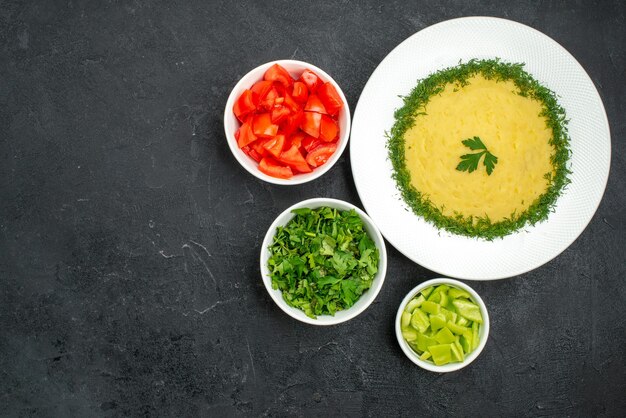 Top view of tasty mushed potatoes with greens and fresh sliced tomatoes on grey