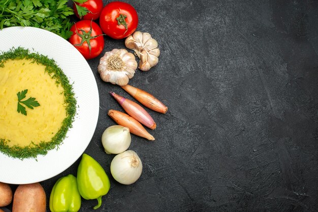 Top view of tasty mushed potatoes with greens and fresh vegetables on black grey