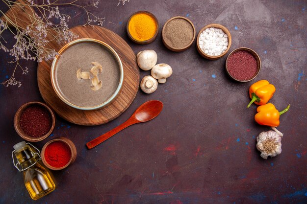 Top view tasty mushroom soup with different seasonings on a dark desk soup mushroom seasoning food meal