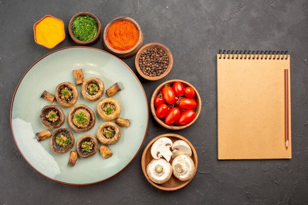 Top view tasty mushrooms meal with fresh tomatoes and seasonings on the dark surface dish dinner meal cooking mushroom