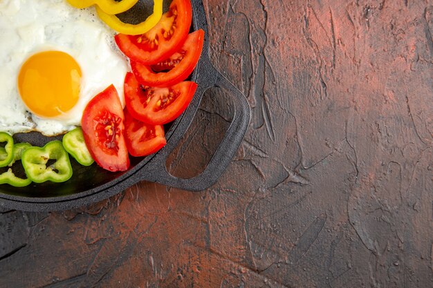 Top view tasty omelette with sliced bell-peppers and tomatoes on a dark table