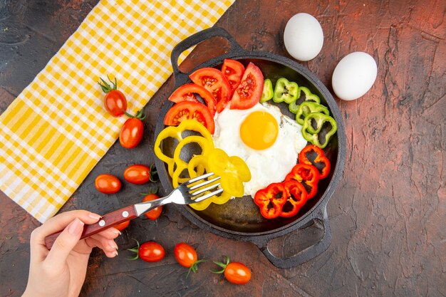 Top view tasty omelette with tomatoes and sliced bell-peppers on a dark table