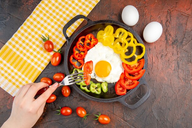 Top view tasty omelette with tomatoes and sliced bell-peppers on dark table