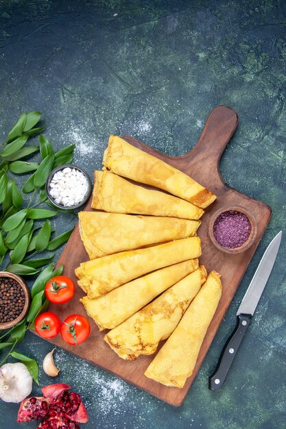 Top view tasty pancakes rolled on a dark blue background pastry hotcake dough pie meat color sweet cake meal