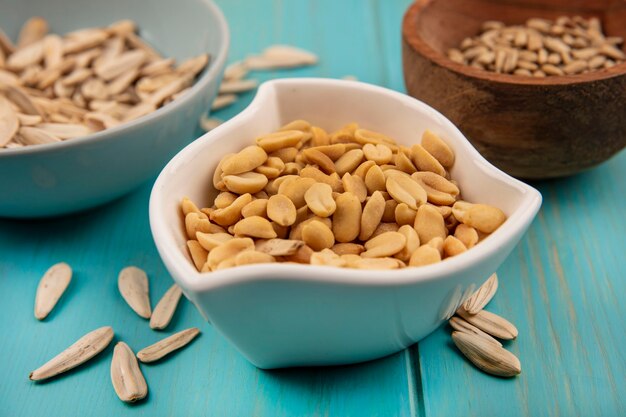 Top view of tasty pine nuts on a white bowl with white sunflower seeds isolated