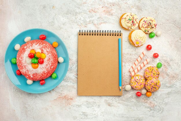 Top view tasty pink cake with yummy cookie cakes on a white surface goodie rainbow candy dessert color cake