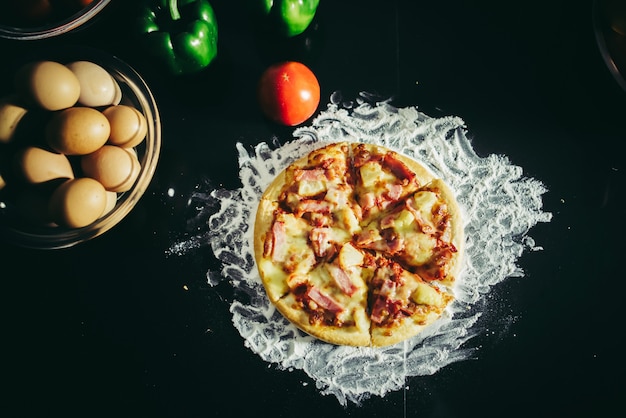 Top view of tasty pizza, cheese and ham on a vintage wooden table.