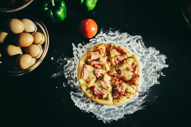 Вид сверху вкусной пиццы, сыра и ветчины на старинном деревянном столе.