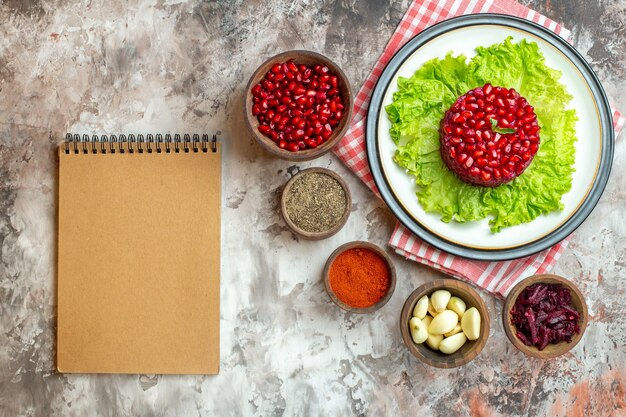 Вид сверху вкусный гранатовый салат на зеленом салате с приправами на светлом фоне