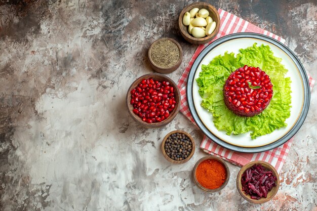 Top view tasty pomegranate salad on green salad with seasonings on light background