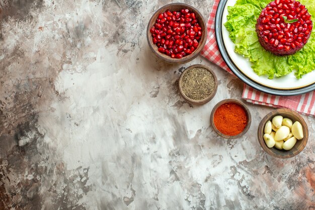 Top view tasty pomegranate salad on green salad with seasonings on light background