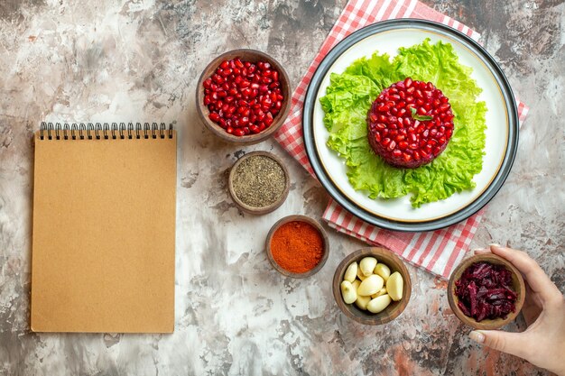 Top view tasty pomegranate salad on green salad with seasonings on light background