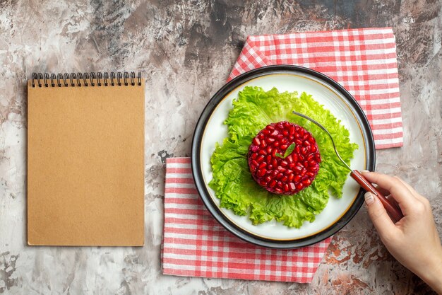 Foto gratuita vista dall'alto gustosa insalata di melograno a forma rotonda su insalata verde sullo sfondo chiaro