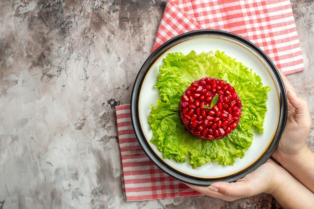 Вид сверху вкусный гранатовый салат круглой формы на зеленом салате на светлом фоне