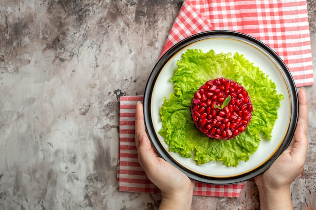 Top view tasty pomegranate salad round shaped on green salad on light background