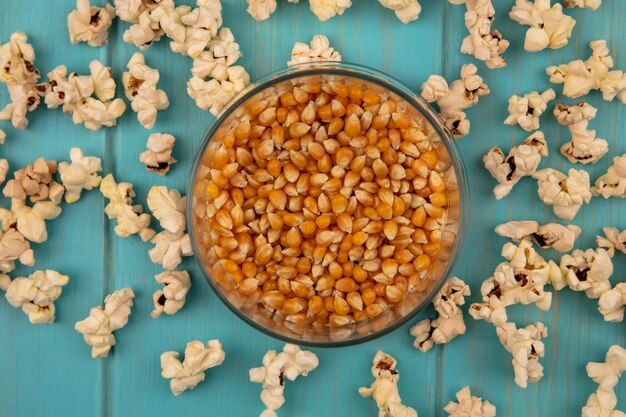 Top view of tasty popcorns kernels on a glass jar with popcorns isolated on a blue wooden table