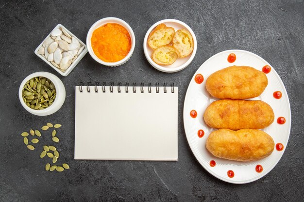 Top view tasty potato hotcakes with mushed pumpkin and its seeds on dark-grey background cake pie hotcake potato meal oil