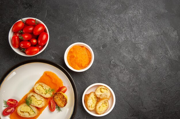 Вид сверху вкусные картофельные пироги с тыквой и свежими помидорами на сером столе, обеденная духовка, выпечка, ломтик цветного блюда