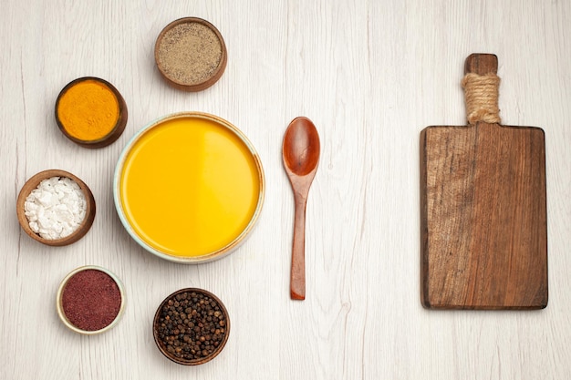 Top view of tasty pumpkin soup cream textured with seasonings on white table