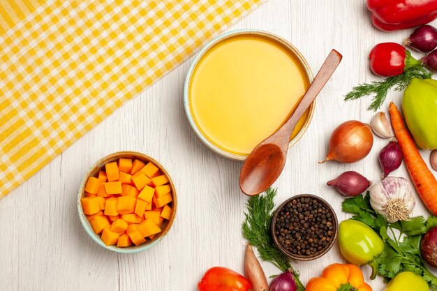 Top view of tasty pumpkin soup cream textured with vegetables on white table