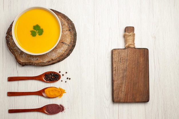 Foto gratuita vista dall'alto di una gustosa zuppa di zucca con pepe su bianco