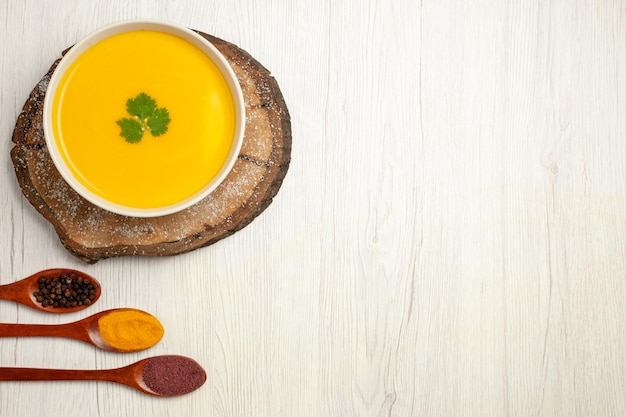 Foto gratuita vista dall'alto di una gustosa zuppa di zucca con condimenti su bianco