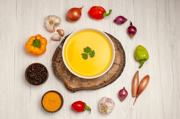 Top view of tasty pumpkin soup with vegetables on white