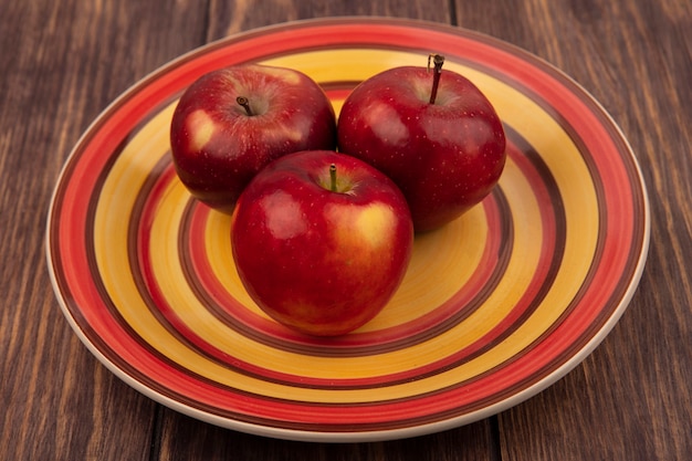 Free photo top view of tasty red apples on a plate on a wooden surface