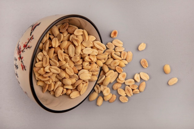 Top view of tasty roasted salty pine nuts falling out of a bowl