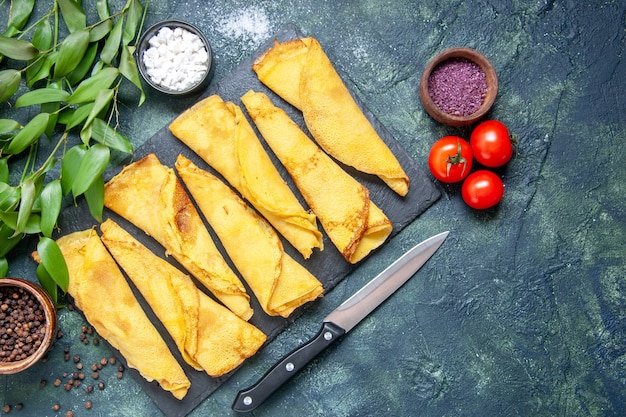 Top view tasty rolled pancakes lined with tomatoes on dark background color meal pie meat dough sweet hotcake pastry cake