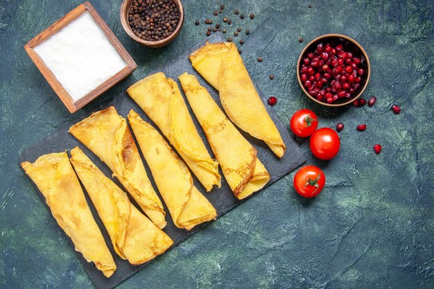 Top view tasty rolled pancakes lined with tomatoes on dark background hotcakes color meal pie meat dough pastry cake sweet