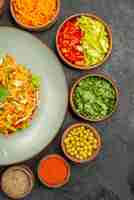 Foto gratuita vista dall'alto gustosa insalata con ingredienti su insalata di salute grigio scuro