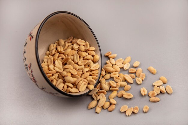 Top view of tasty and salty pine nuts falling out of a bowl