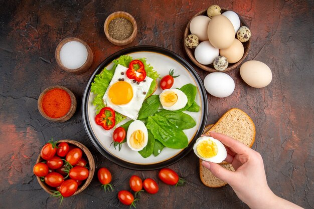 어두운 테이블에 조리된 계란과 토마토가 있는 맛있는 샌드위치