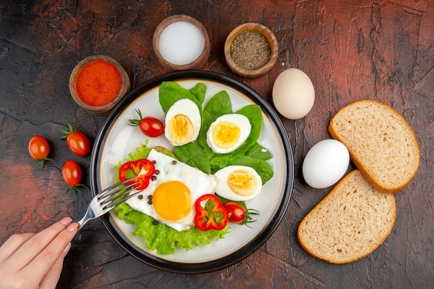 Top view tasty sandwich with eggs seasonings and tomatoes on dark table