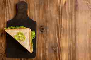 Free photo top view of tasty sandwich with green salad tomatoes on the brown wooden surface