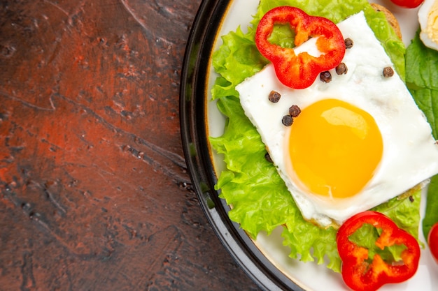 Top view tasty sandwich with scrambled and boiled eggs and salad inside plate on dark table