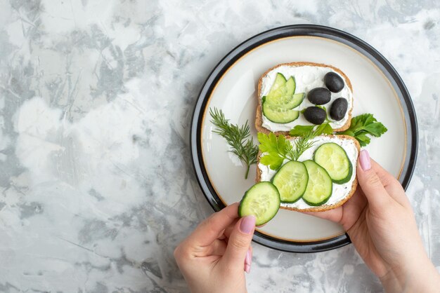 Вид сверху вкусные бутерброды с огурцами и оливками внутри тарелки на белом фоне еда здоровая еда хлеб обед горизонтальный тост бургер женщина