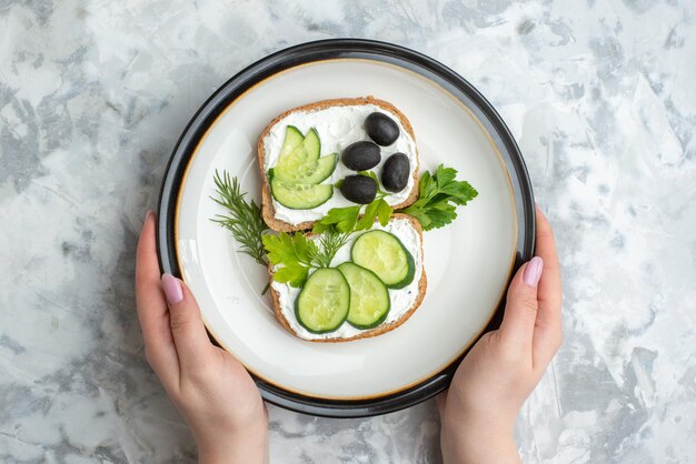 上面図白い背景のプレートの内側にきゅうりとオリーブのおいしいサンドイッチ食品健康食事パンランチ水平トーストバーガー