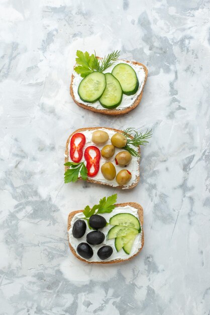 Вид сверху вкусные бутерброды с огурцами и оливками на белом фоне обед еда бутерброд еда бургер хлеб тост