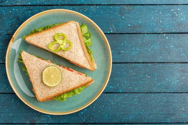 Top view of tasty sandwiches with green salad and ham inside plate