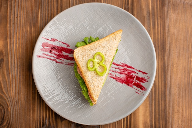 Top view of tasty sandwiches with green salad tomatoes on the brown surface