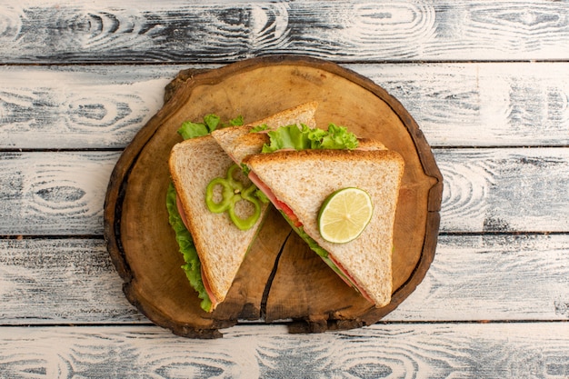 Top view of tasty sandwiches on the wooden desk and grey rustic surface