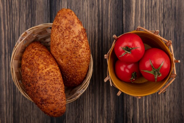 나무 배경에 양동이에 신선한 빨간 토마토와 양동이에 맛있는 참깨 버거의 상위 뷰