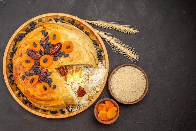 Top view of tasty shakh plov with raisins and dried apricots on dark surface