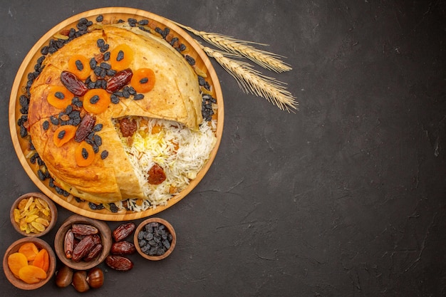 Top view of tasty shakh plov with raisins and dried apricots on dark surface