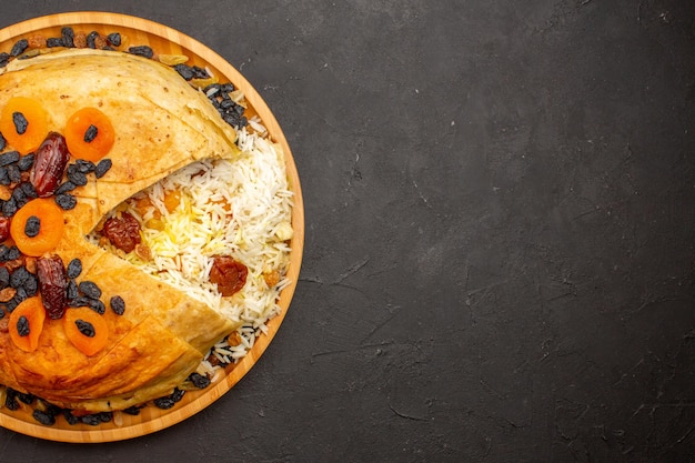 Free photo top view of tasty shakh plov with raisins and dried apricots on the dark surface