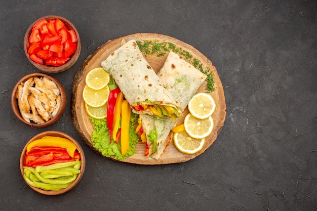 Vista dall'alto del gustoso sandwich di pollo a fette di shaurma con fette di limone al buio